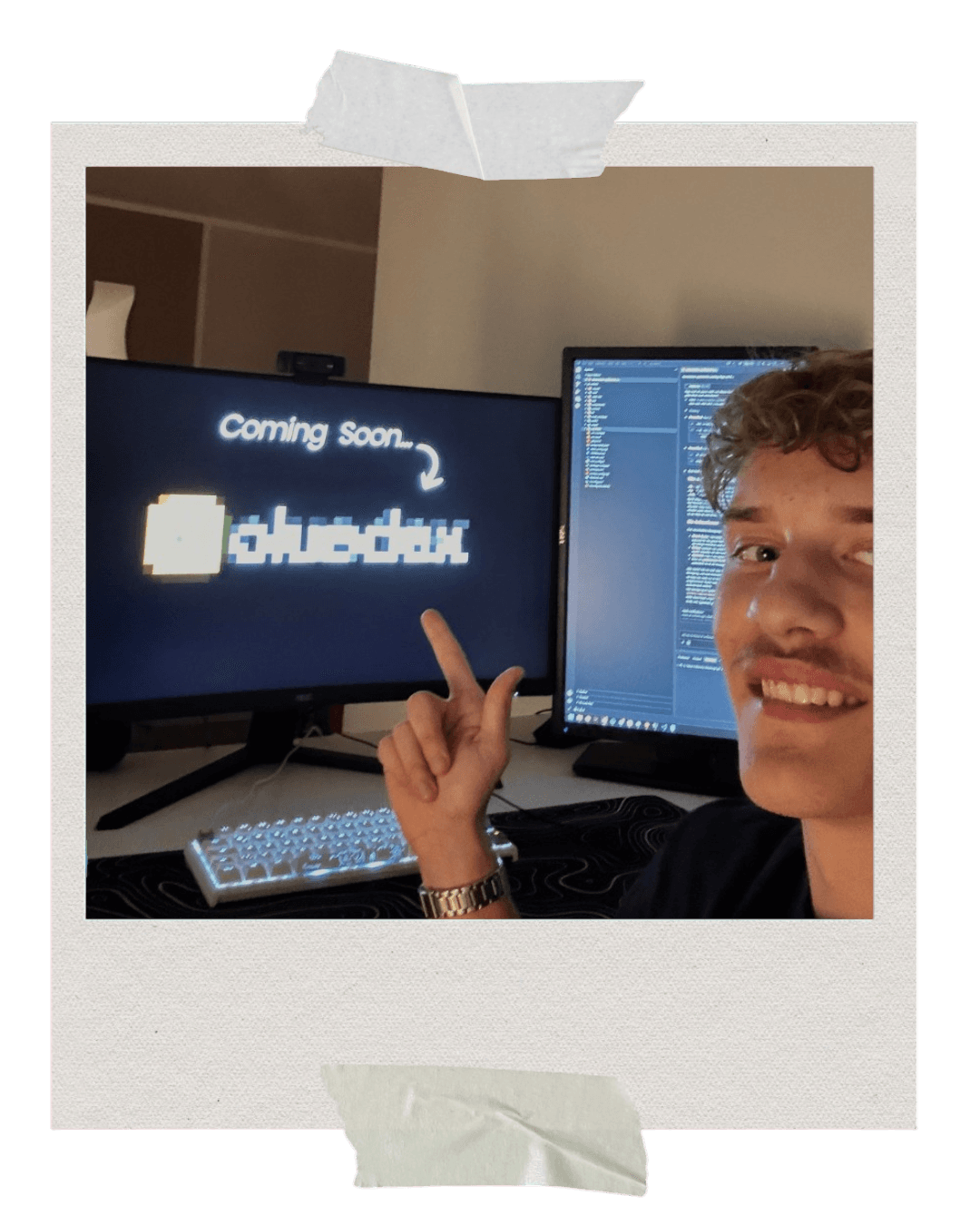 Dennis vor seinem Schreibtisch, im Hintergrund zwei Bildschirme mit einer «Coming Soon»-Seite und geöffnetem Code